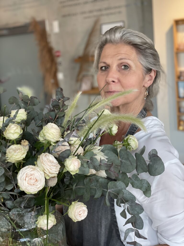 Auf dem Bild ist Silke Möbius von der "Flachsblüte" mit einem Strauß weißer Blumen zu sehen. Mit Ihr können zu VORFREUDE Adventskränze gebunden werden.