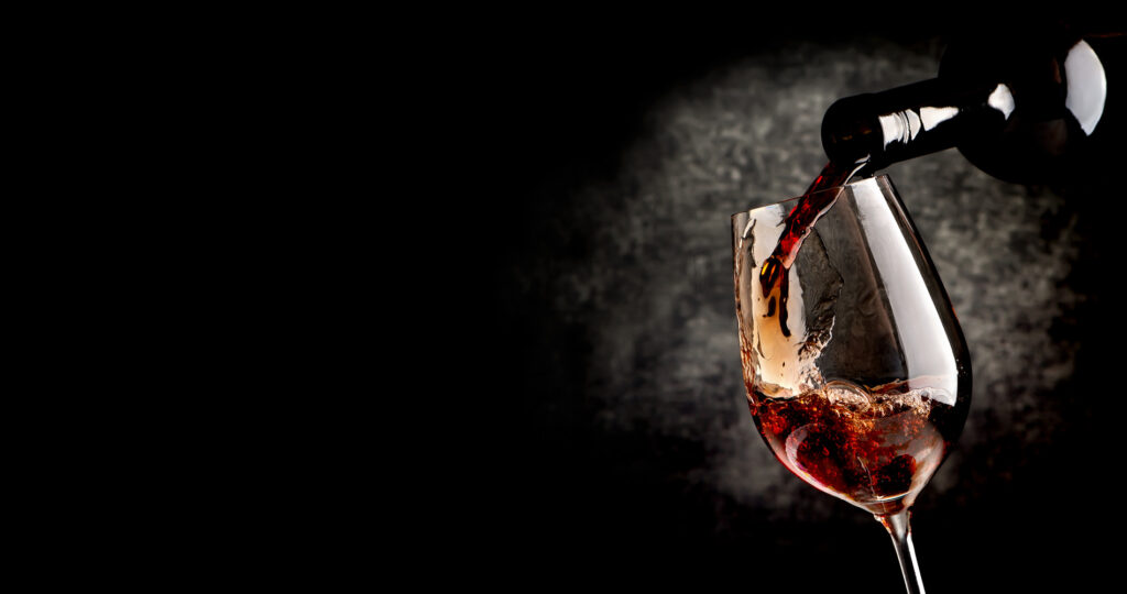 Das Bild zeigt ein Glas in das Rotwein geschenkt wird mit einer mystischen Wolke im Hintergrund, sinnbildlich für die Weinverkostung Wein und Stadtgeschichte(n)