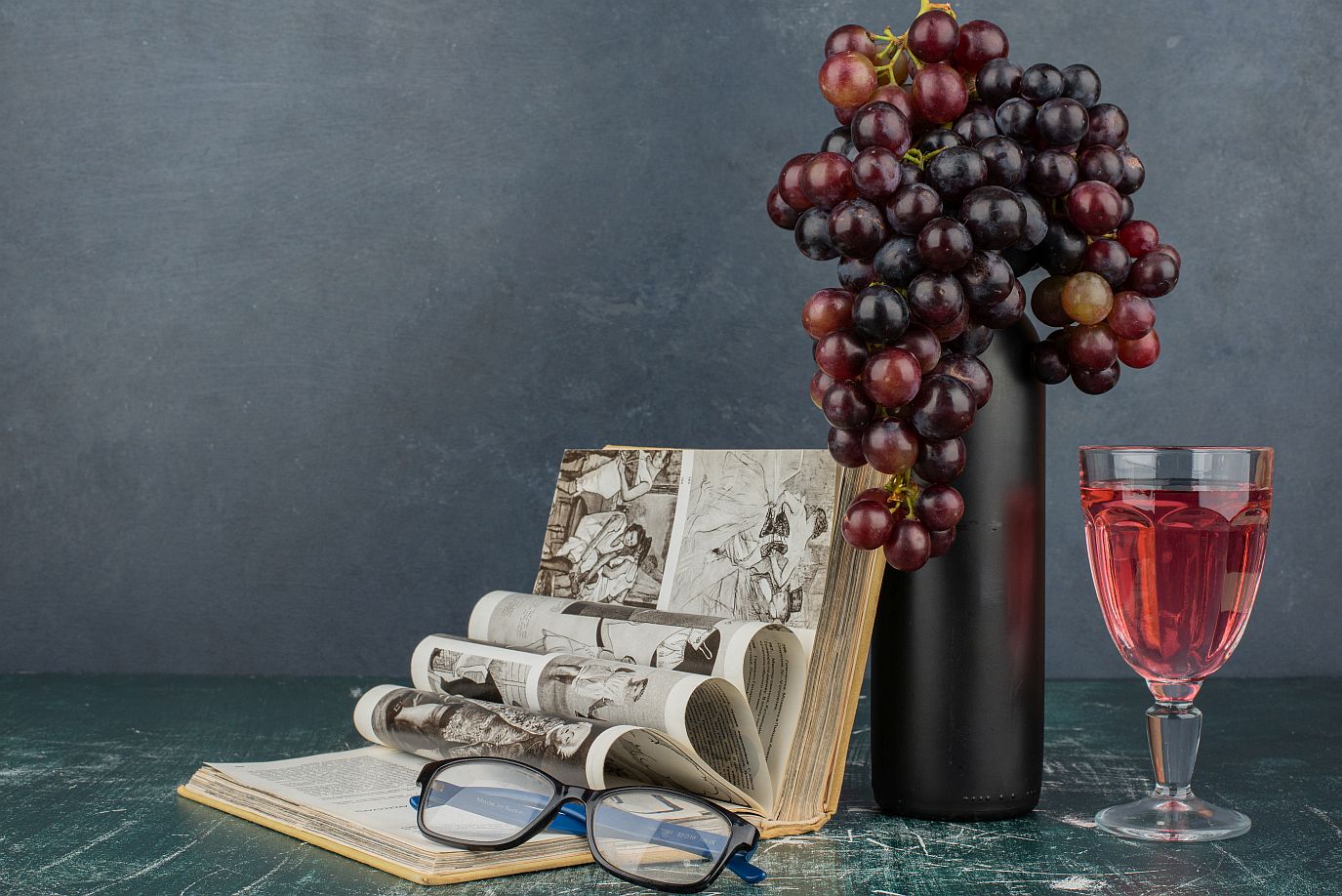Wein und Bücher - das Bild für die WeinLese mit Weinflasche und Trauben, Weinglas und Buch.